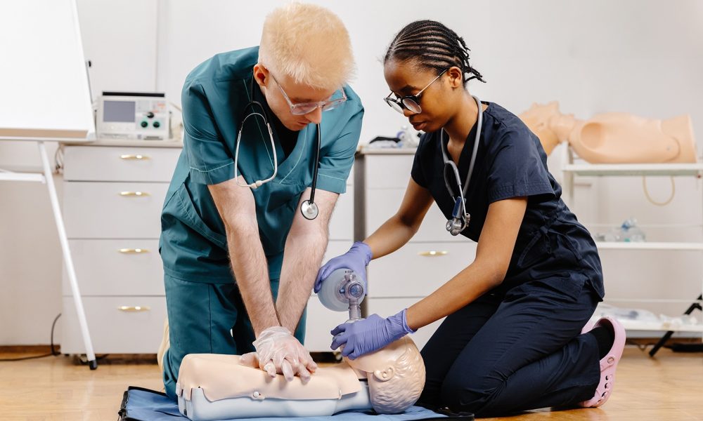 Two medical professionals practice CPR on a training mannequin, demonstrating proper technique and teamwork.